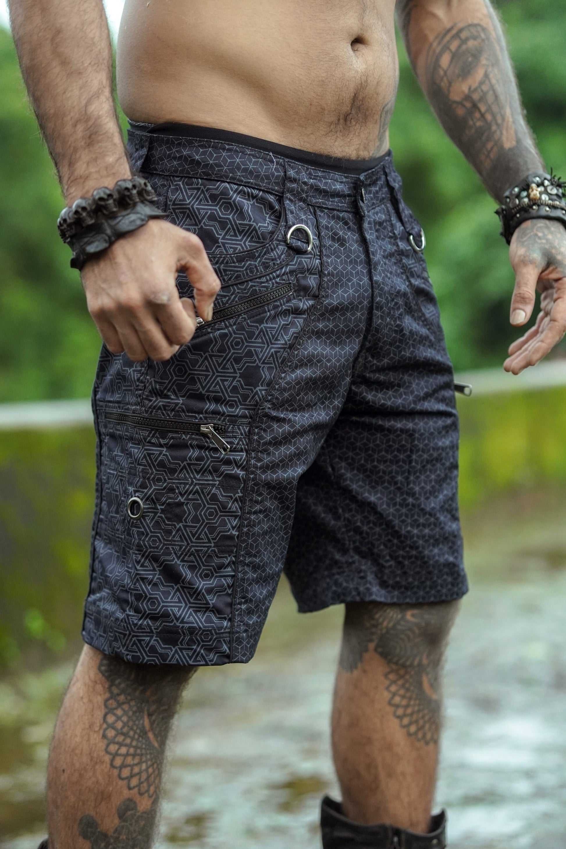 A pair of men's up-knee black shorts with a geometric pattern, featuring multiple pockets and YKK zippers.